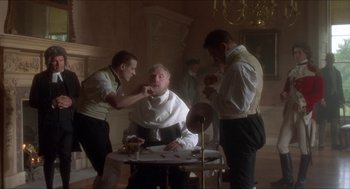 Movie still from “The Madness of King George” (1994), directed by Nicholas Hytner – A group of men standing around a man getting his hair cut; Medium shot, Low angle