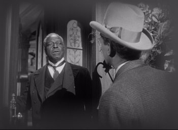 Movie still from “The Magnificent Ambersons” (1942), directed by Robert Wise – A man in a suit and tie talking to another man in a hat; Medium shot, Over the shoulder angle