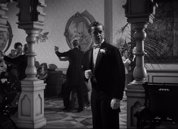 Movie still from “The Magnificent Ambersons” (1942), directed by Robert Wise – A man in a tuxedo standing next to two other men in tuxedos; Medium shot, Over the shoulder angle