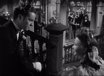 Movie still from “The Magnificent Ambersons” (1942), directed by Robert Wise – A man and a woman in formal wear standing next to a railing; Medium shot, Over the shoulder angle
