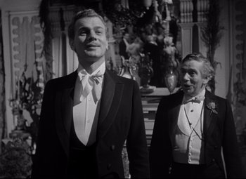 Movie still from “The Magnificent Ambersons” (1942), directed by Robert Wise – A man in a suit and tie next to another man in a suit and tie; Medium shot, Low angle