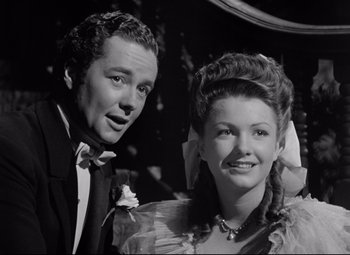 Movie still from “The Magnificent Ambersons” (1942), directed by Robert Wise – A man and a woman posing for a picture; Medium shot, Low angle