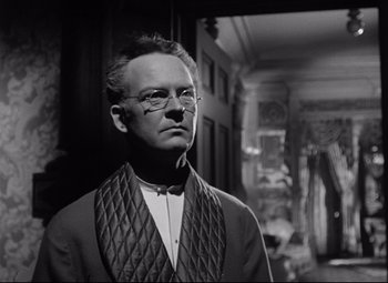 Movie still from “The Magnificent Ambersons” (1942), directed by Robert Wise – An old man wearing glasses standing in front of a mirror; Close Up shot, Low angle