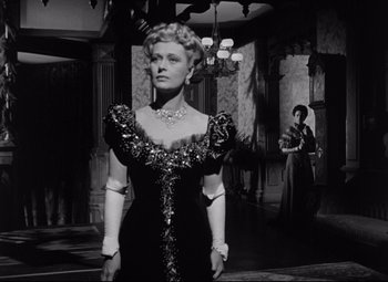 Movie still from “The Magnificent Ambersons” (1942), directed by Robert Wise – A woman in a black dress standing in front of a mirror; Medium shot, Low angle