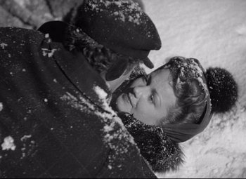 Movie still from “The Magnificent Ambersons” (1942), directed by Robert Wise – A woman in a hat and a coat in the middle of a snow covered field; Medium shot, Over the shoulder angle