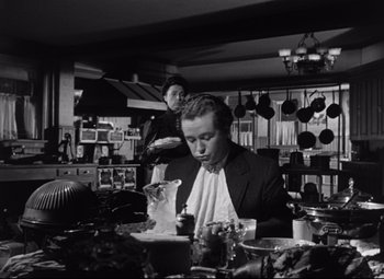 Movie still from “The Magnificent Ambersons” (1942), directed by Robert Wise – A man sitting at a table in front of another man; Medium shot, Low angle