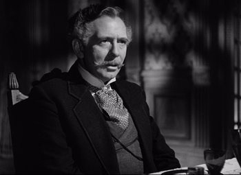 Movie still from “The Magnificent Ambersons” (1942), directed by Robert Wise – An older man in a suit sitting in a chair; Close Up shot, Over the shoulder angle