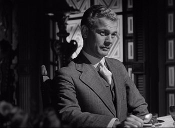 Movie still from “The Magnificent Ambersons” (1942), directed by Robert Wise – A man sitting in a chair wearing a suit and tie; Medium shot, Low angle