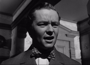 Movie still from “The Magnificent Ambersons” (1942), directed by Robert Wise – A man in a suit and a bow tie; Close Up shot, Low angle