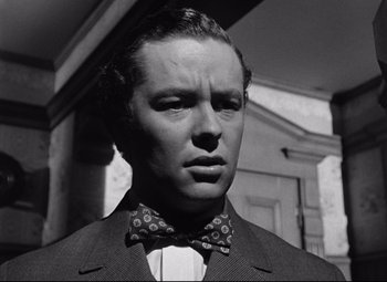 Movie still from “The Magnificent Ambersons” (1942), directed by Robert Wise – A black and white photo of a man wearing a suit and bow tie; Close Up shot, Low angle