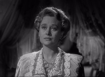 Movie still from “The Magnificent Ambersons” (1942), directed by Robert Wise – An old photo of a woman in a dress looking at the camera; Close Up shot, Low angle