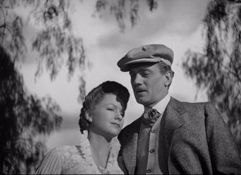 Movie still from “The Magnificent Ambersons” (1942), directed by Robert Wise – A man and a woman standing next to each other in front of a tree; Medium shot, Low angle