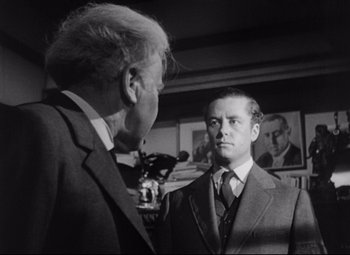 Movie still from “The Magnificent Ambersons” (1942), directed by Robert Wise – A man in a suit talks to another man in a suit; Medium shot, Over the shoulder angle
