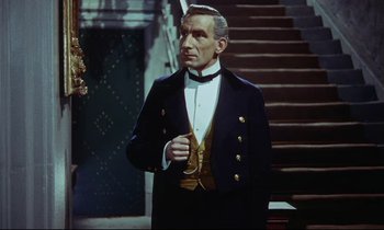 Movie still from “The Man Who Could Cheat Death” (1959), directed by Terence Fisher – A man in a suit standing in front of a staircase; Medium shot, High angle