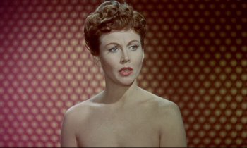 Movie still from “The Man Who Could Cheat Death” (1959), directed by Terence Fisher – A woman with a bare chest is posing for the camera; Close Up shot, Over the shoulder angle