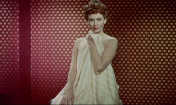 Movie still from “The Man Who Could Cheat Death” (1959), directed by Terence Fisher – A woman in a white dress holding a towel; Medium shot, Low angle