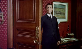Movie still from “The Man Who Could Cheat Death” (1959), directed by Terence Fisher – A man standing in front of a wooden door; Medium shot, Low angle