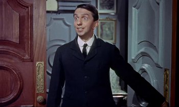 Movie still from “The Man Who Could Cheat Death” (1959), directed by Terence Fisher – A man in a suit and tie standing in front of a door; Medium shot, Low angle