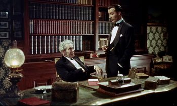 Movie still from “The Man Who Could Cheat Death” (1959), directed by Terence Fisher – A man in a suit and a tie standing next to another man in a suit and a tie; Medium shot, High angle