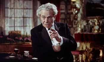 Movie still from “The Man Who Could Cheat Death” (1959), directed by Terence Fisher – An older man wearing a suit and tie holding a tie; Medium shot, High angle