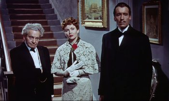 Movie still from “The Man Who Could Cheat Death” (1959), directed by Terence Fisher – A group of people standing next to each other in front of a staircase; Medium shot, Low angle