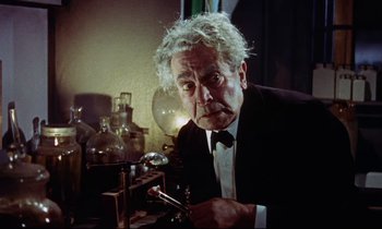 Movie still from “The Man Who Could Cheat Death” (1959), directed by Terence Fisher – An older man in a black suit and white tie; Medium shot, Low angle
