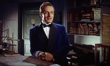 Movie still from “The Man Who Could Cheat Death” (1959), directed by Terence Fisher – A man in a blue velvet jacket standing in front of a book shelf; Medium shot, Low angle
