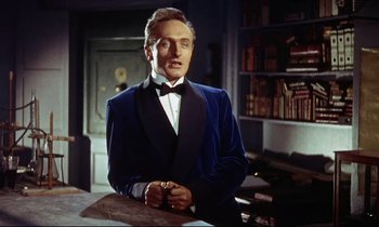 Movie still from “The Man Who Could Cheat Death” (1959), directed by Terence Fisher – A man in a blue velvet jacket standing in front of a book shelf; Medium shot, Low angle