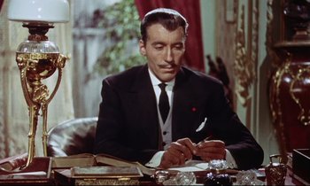 Movie still from “The Man Who Could Cheat Death” (1959), directed by Terence Fisher – A man sitting at a table writing on a piece of paper; Medium shot, Low angle