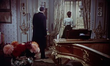 Movie still from “The Man Who Could Cheat Death” (1959), directed by Terence Fisher – A man and a woman standing in front of a window; Wide shot, High angle