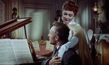 Movie still from “The Man Who Could Cheat Death” (1959), directed by Terence Fisher – A woman standing next to a man in front of a grand piano; Medium shot, Over the shoulder angle