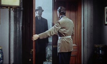 Movie still from “The Man Who Could Cheat Death” (1959), directed by Terence Fisher – A man in a suit and hat standing in front of an open door; Medium shot, Over the shoulder angle