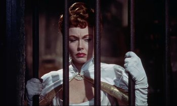 Movie still from “The Man Who Could Cheat Death” (1959), directed by Terence Fisher – A woman in a white dress behind a metal fence; Close Up shot, Low angle