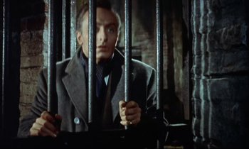 Movie still from “The Man Who Could Cheat Death” (1959), directed by Terence Fisher – A man standing behind bars in a jail cell; Close Up shot, Low angle
