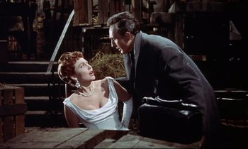 Movie still from “The Man Who Could Cheat Death” (1959), directed by Terence Fisher – A man and a woman sitting next to each other on a table; Medium shot, Low angle