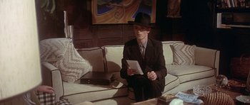 Movie still from “The Man Who Fell to Earth” (1976), directed by Nicolas Roeg – A man sitting on top of a couch holding a tablet; Medium shot, High angle