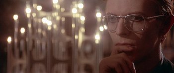 Movie still from “The Man Who Fell to Earth” (1976), directed by Nicolas Roeg – A man with glasses is looking out a window; Close Up shot, Over the shoulder angle