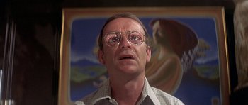 Movie still from “The Man Who Fell to Earth” (1976), directed by Nicolas Roeg – A man with glasses is looking at the camera; Close Up shot, Low angle