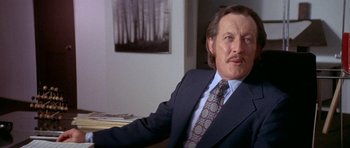 Movie still from “The Man Who Fell to Earth” (1976), directed by Nicolas Roeg – A man in a suit and tie sitting at a table; Close Up shot, Low angle