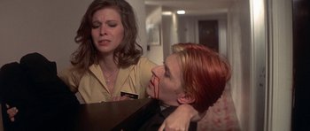 Movie still from “The Man Who Fell to Earth” (1976), directed by Nicolas Roeg – A woman holding a man's face with blood on it; Medium shot, Over the shoulder angle