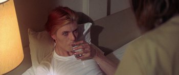 Movie still from “The Man Who Fell to Earth” (1976), directed by Nicolas Roeg – A man in white shirt drinking a glass of water; Close Up shot, High angle