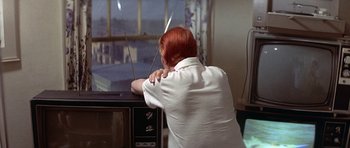 Movie still from “The Man Who Fell to Earth” (1976), directed by Nicolas Roeg – A woman sitting in front of an old television; Medium shot, High angle