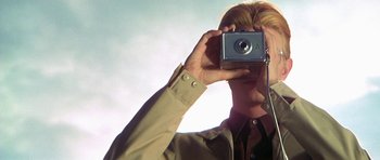 Movie still from “The Man Who Fell to Earth” (1976), directed by Nicolas Roeg – A man taking a picture with a camera; Extreme Close Up shot, Low angle