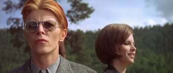 Movie still from “The Man Who Fell to Earth” (1976), directed by Nicolas Roeg – A man and a woman are standing next to each other; Close Up shot, Low angle