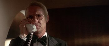 Movie still from “The Man Who Fell to Earth” (1976), directed by Nicolas Roeg – An older man in a tuxedo is holding a microphone in his hand; Close Up shot, Low angle