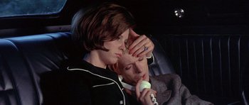 Movie still from “The Man Who Fell to Earth” (1976), directed by Nicolas Roeg – A couple of people sitting in the back of a car; Close Up shot, High angle