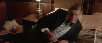 Movie still from “The Man Who Fell to Earth” (1976), directed by Nicolas Roeg – A man in a tuxedo sitting in front of a computer keyboard; Medium shot, Low angle