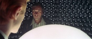 Movie still from “The Man Who Fell to Earth” (1976), directed by Nicolas Roeg – A man is looking into a mirror in a room; Close Up shot, Low angle