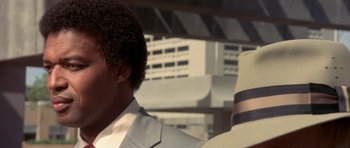 Movie still from “The Man Who Fell to Earth” (1976), directed by Nicolas Roeg – A person wearing a suit and a hat; Close Up shot, Low angle