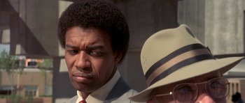 Movie still from “The Man Who Fell to Earth” (1976), directed by Nicolas Roeg – A person wearing a suit and a hat; Close Up shot, Over the shoulder angle